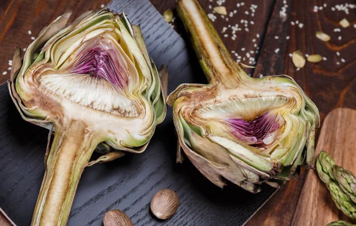 Image of artichoke halves on a black cutting board