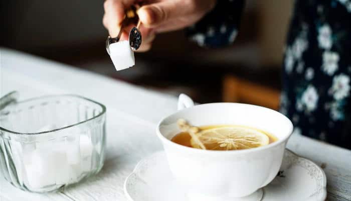 Person adding sugar to tea